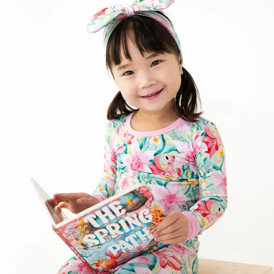 Child wearing a floral dress holding a book with a white background