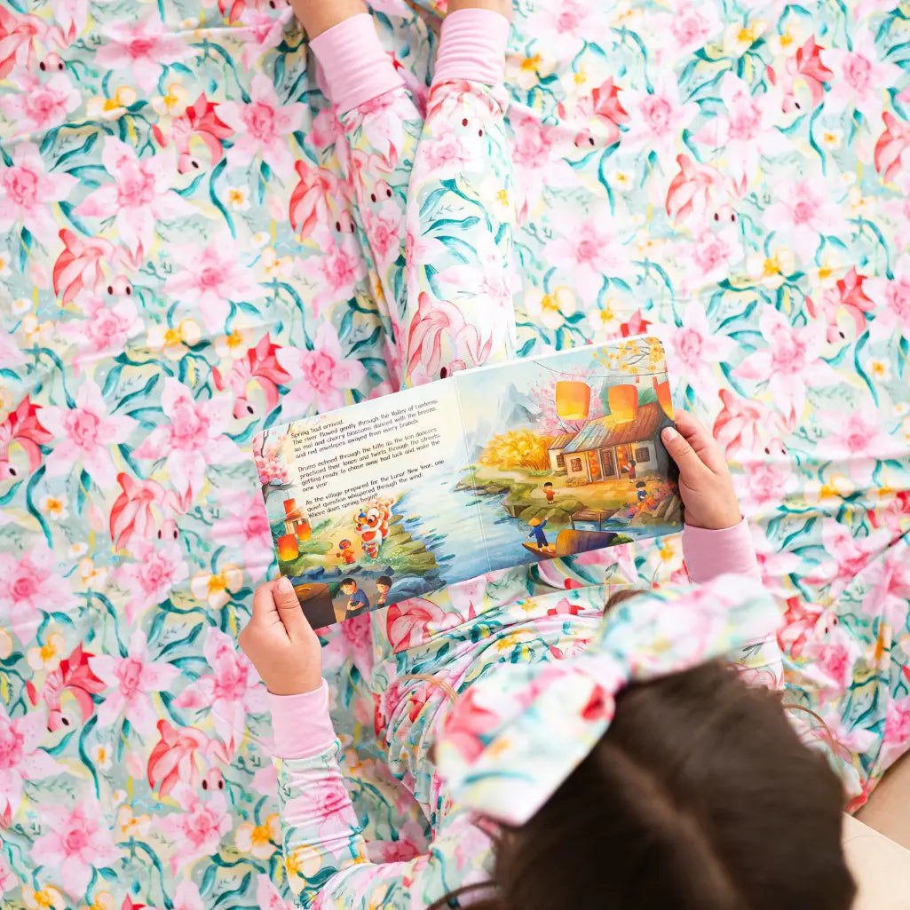 Child reading a book on a floral-patterned bedspread