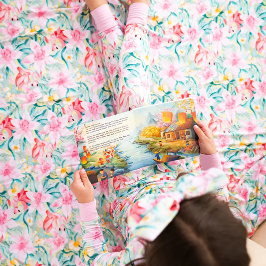 Child reading a book on a floral-patterned bedspread
