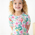 Child wearing a colorful floral and sea-themed shirt on a white background