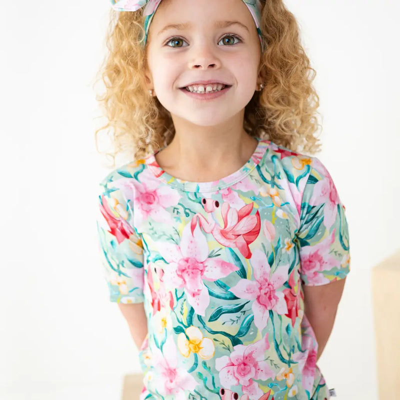 Child wearing a colorful floral and sea-themed shirt on a white background