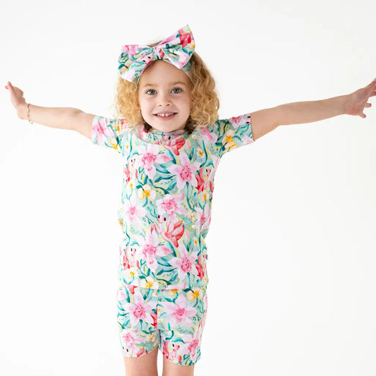 Child wearing a floral swimsuit and headband on a white background
