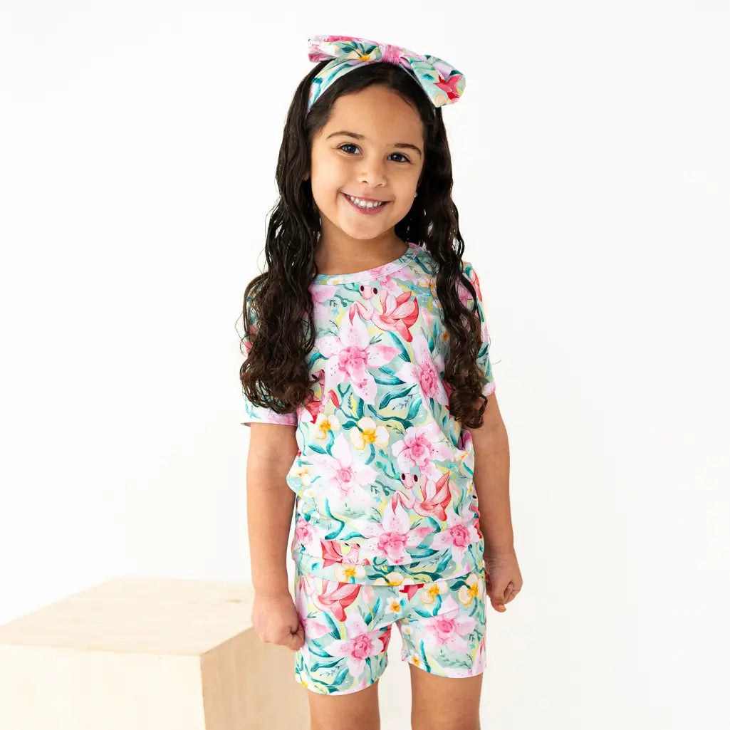 Young girl wearing a floral outfit with a matching headband on a white background