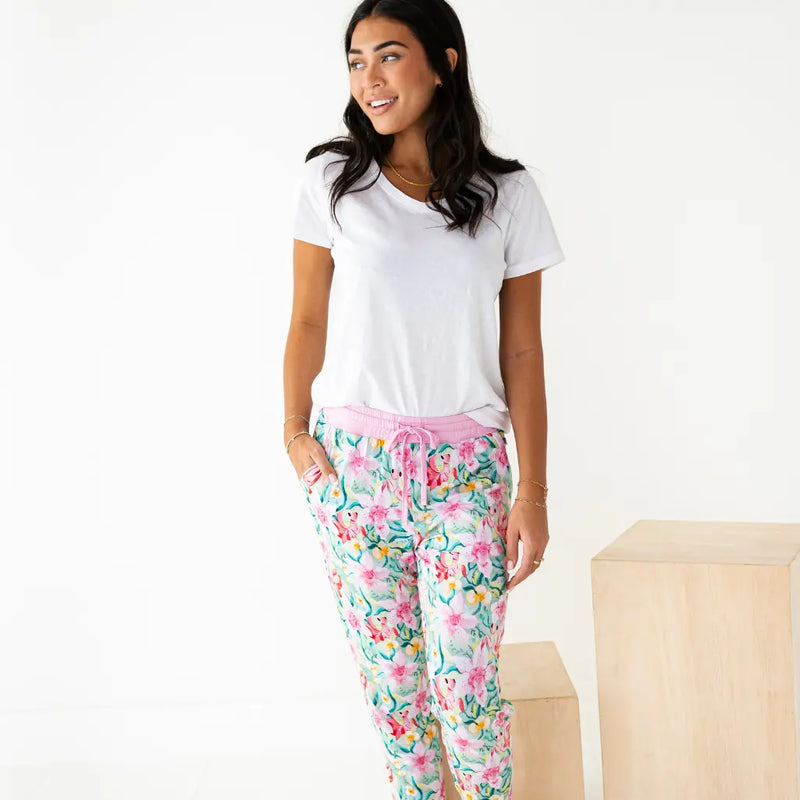 Woman wearing a white t-shirt and floral pajama pants on a plain background