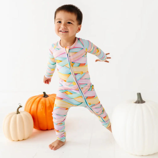 Child wearing a colorful striped onesie with pumpkins in the background