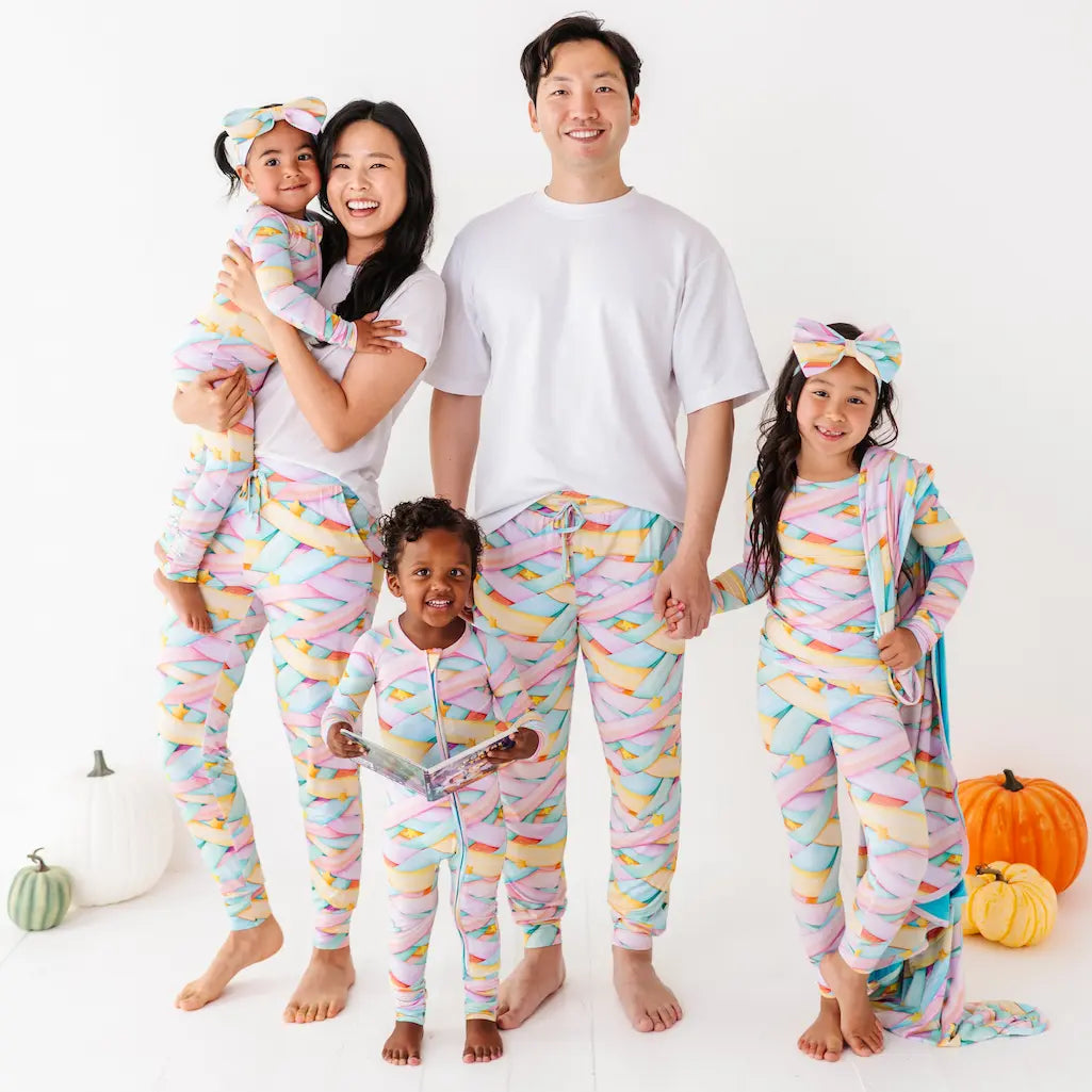 Family of five wearing colorful pajamas with pumpkins in the background