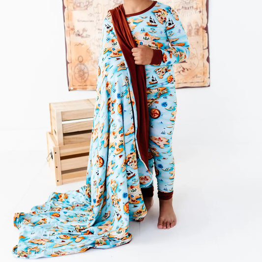 Child wearing a blue pajama set with airplane pattern, holding a matching blanket.
