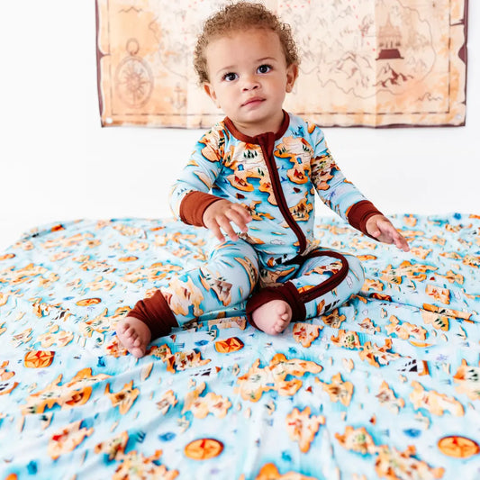 Baby sitting on a colorful blanket with a patterned wall in the background