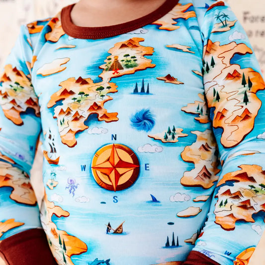 Children's long-sleeve shirt with a map design featuring mountains, compass, and landscapes.