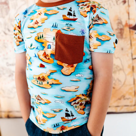 Child wearing a shirt with a map design and ship illustration.