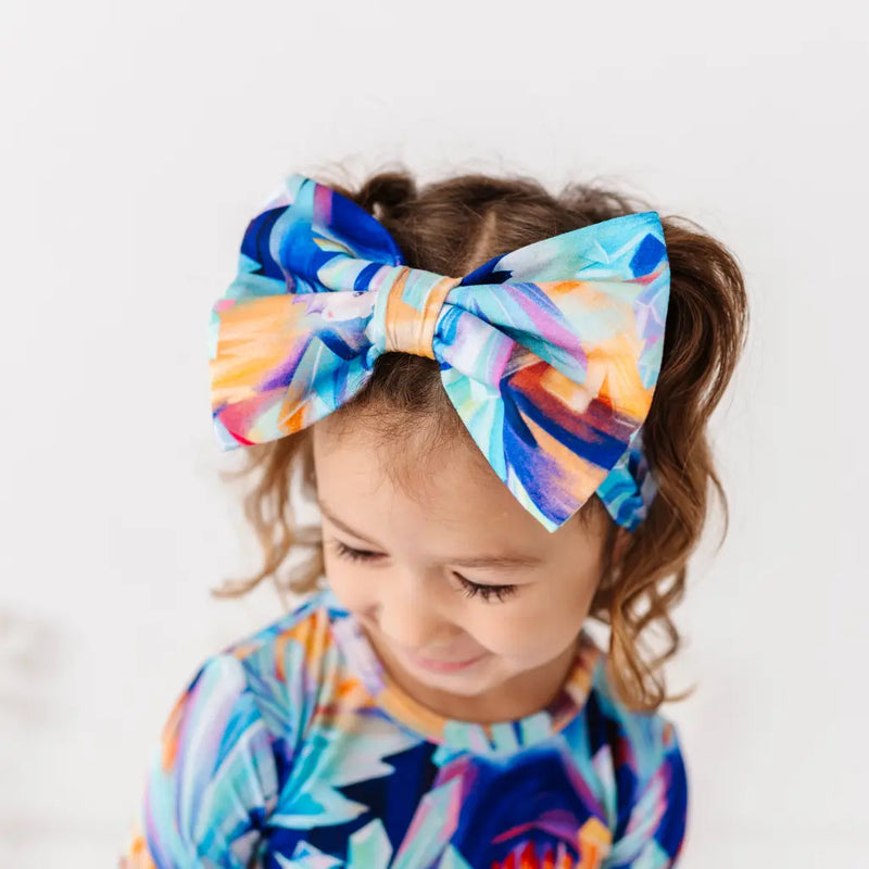 Child wearing a colorful headband with a large bow on a white background