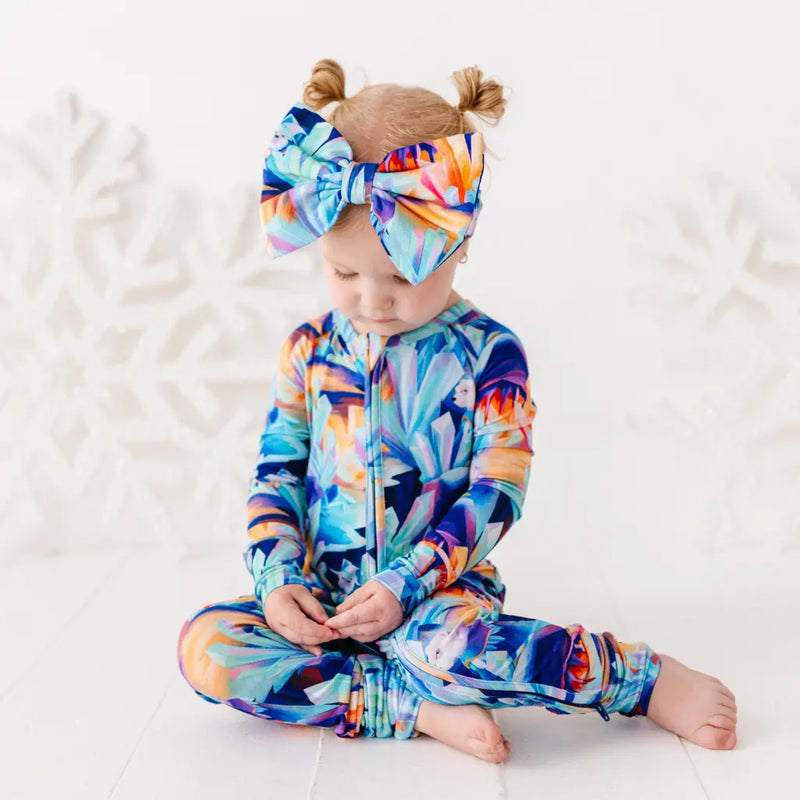 Child wearing a colorful onesie and headband on a white background
