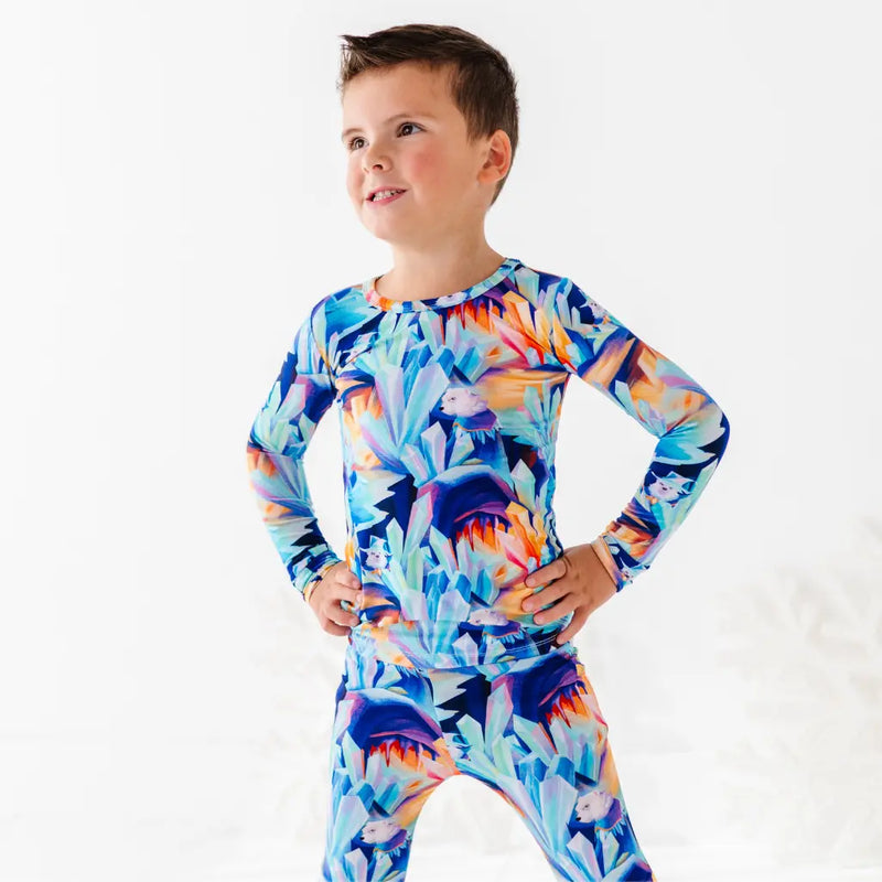 Child wearing a colorful long-sleeve shirt with a floral pattern on a white background