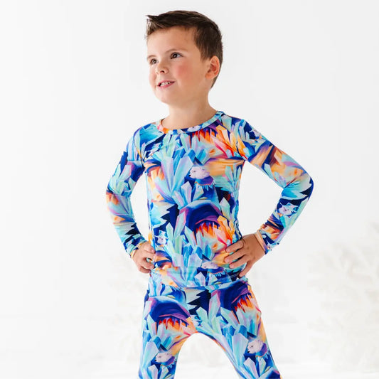Child wearing a colorful long-sleeve shirt with a floral pattern on a white background