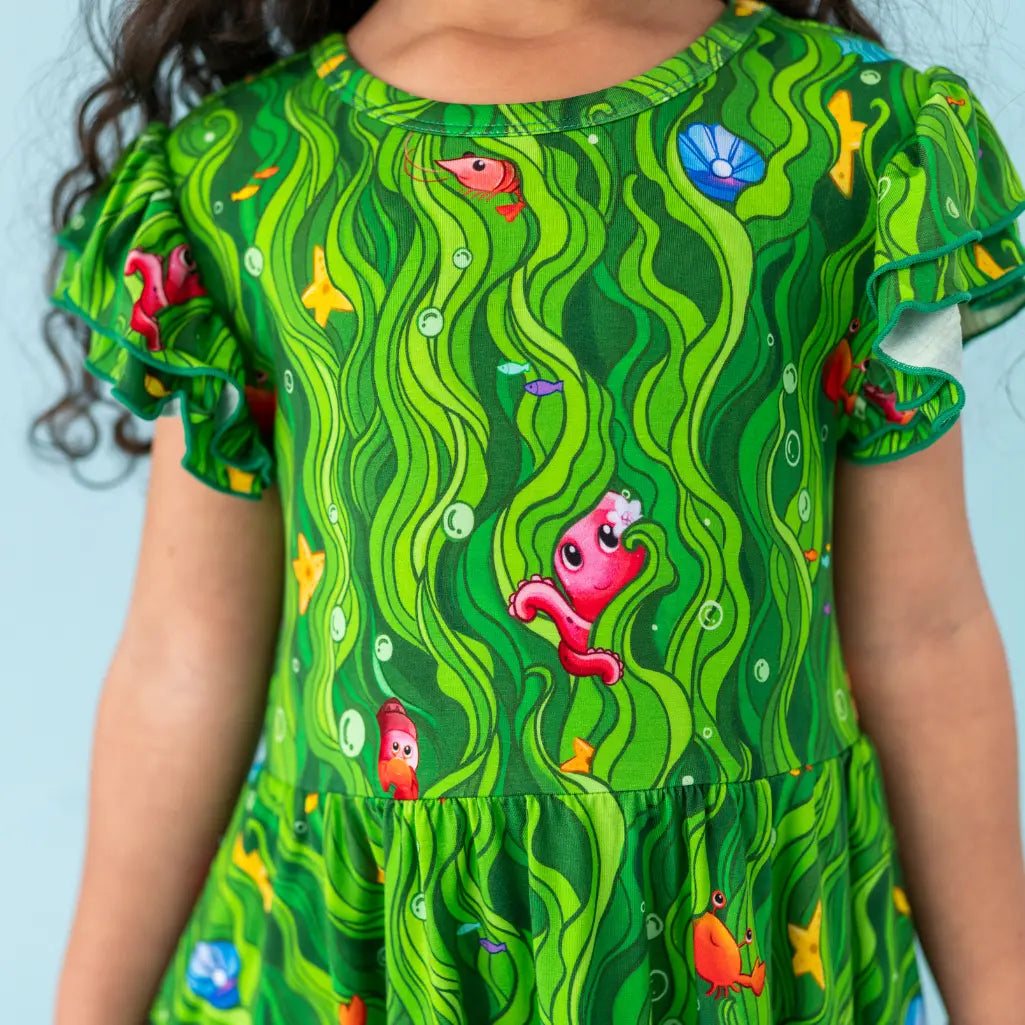 Child wearing a green dress with underwater-themed pattern