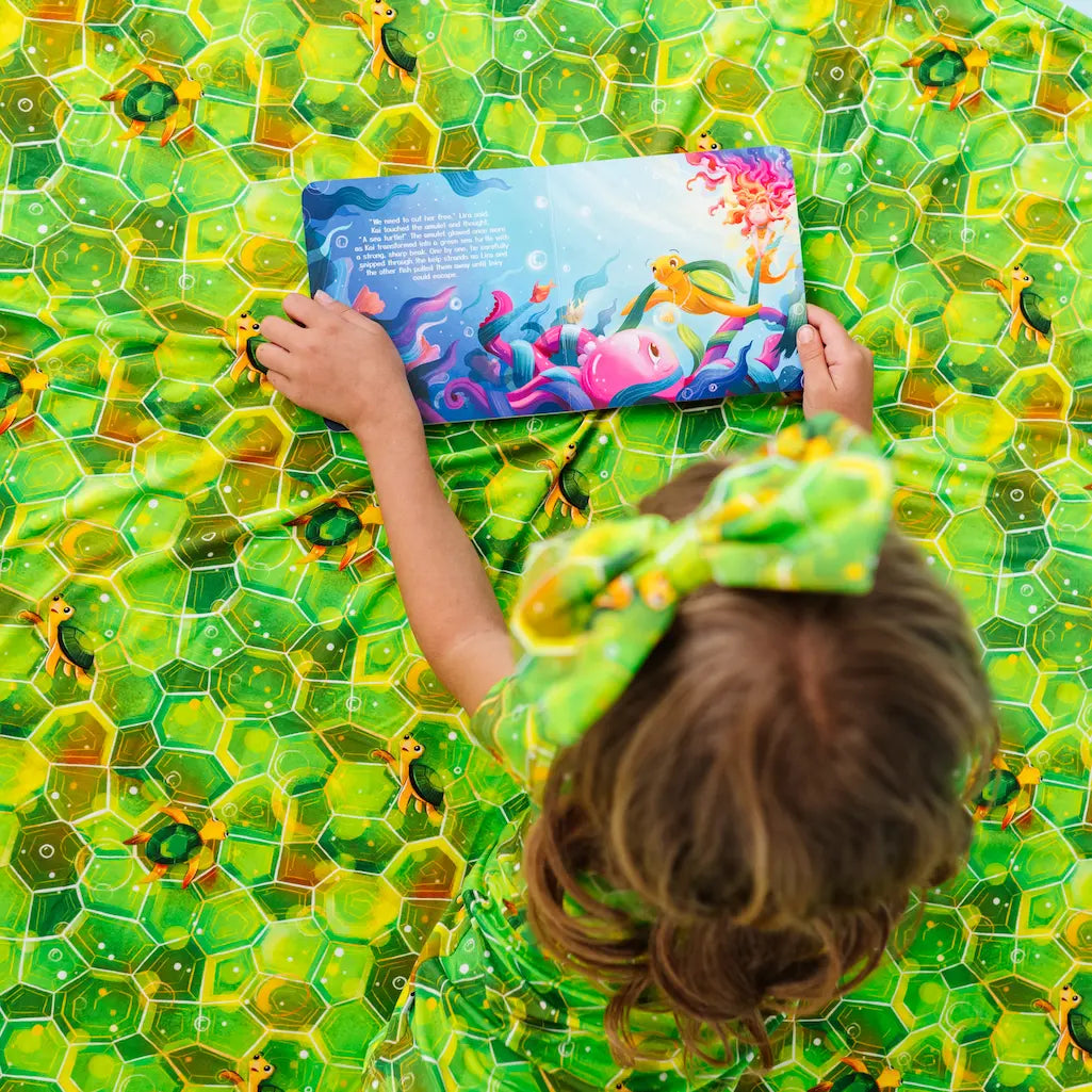 Child holding a colorful book on a green textured surface