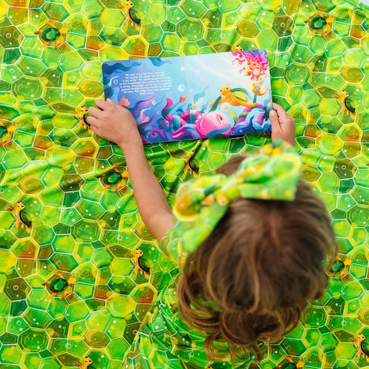 Child holding a colorful book on a green textured surface