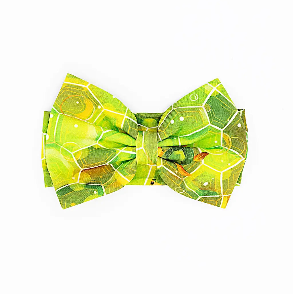 A green bow headband with a geometric shell pattern inspired by Kai the Sea Turtle.