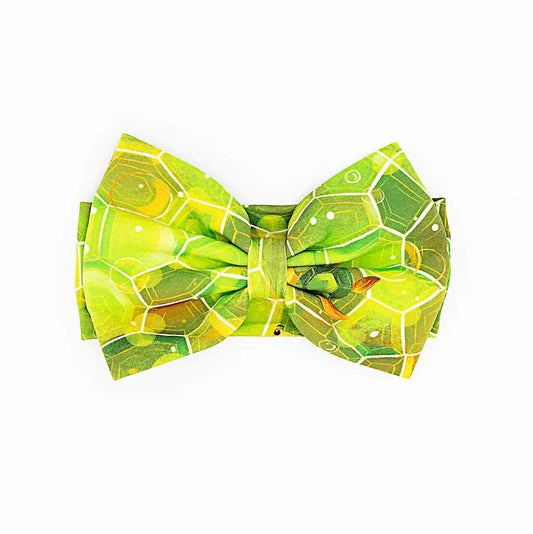 A green bow headband with a geometric shell pattern inspired by Kai the Sea Turtle.