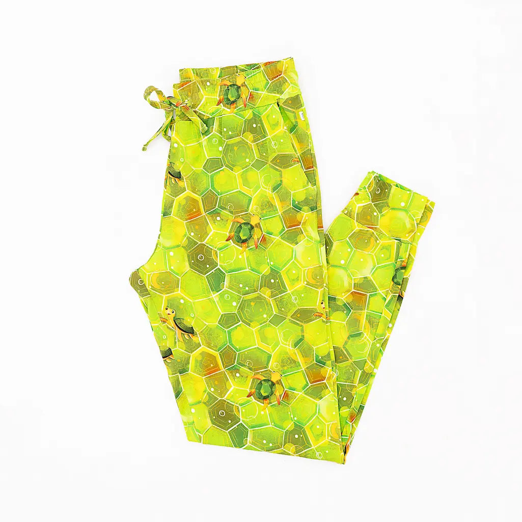 A pair of women's pajama pants with a geometric green shell pattern and hexagonal turtles.