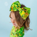 A child wearing a green headband with a geometric sea turtle pattern.