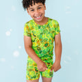 Child wearing a green and yellow patterned swimsuit on a blue background.