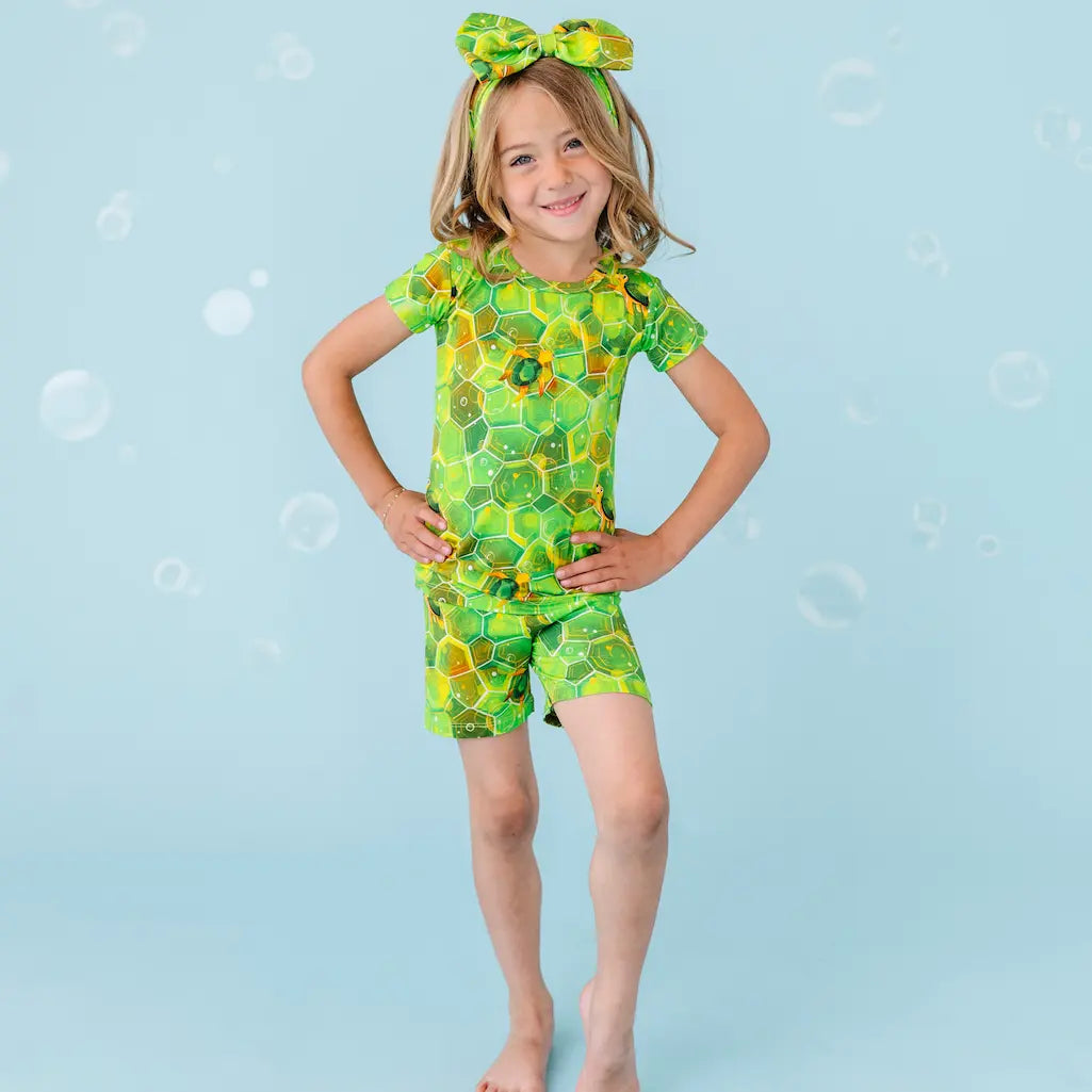 Young girl in a green and yellow patterned swimsuit on a blue background with bubbles.