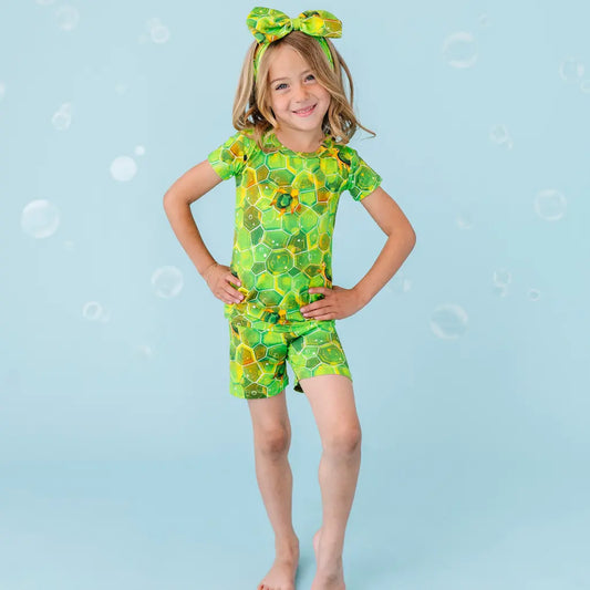 Young girl in a green and yellow patterned swimsuit on a blue background with bubbles.