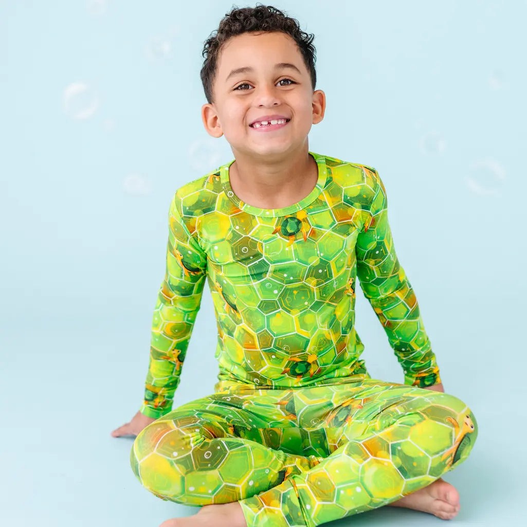 Child wearing a green and yellow patterned swimsuit on a blue background.