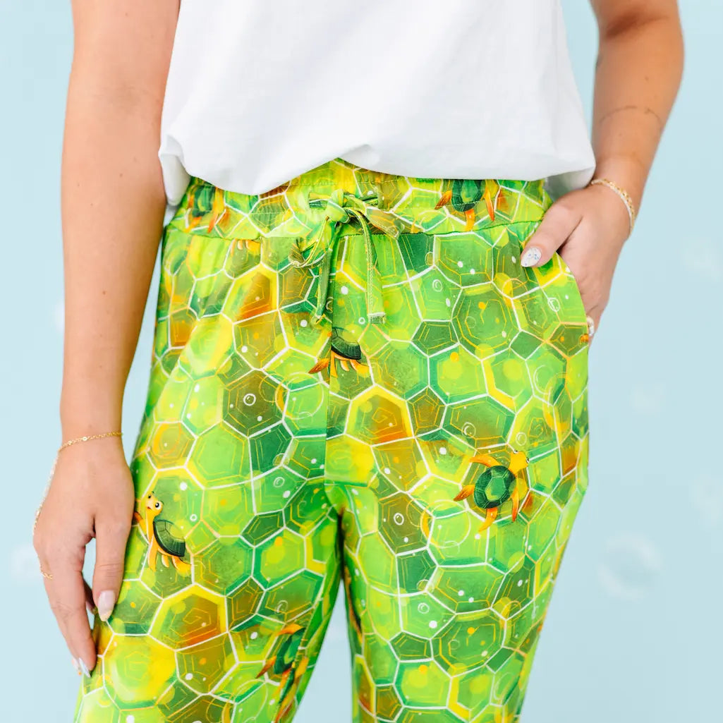 Green honeycomb patterned pants worn by a person against a light blue background.