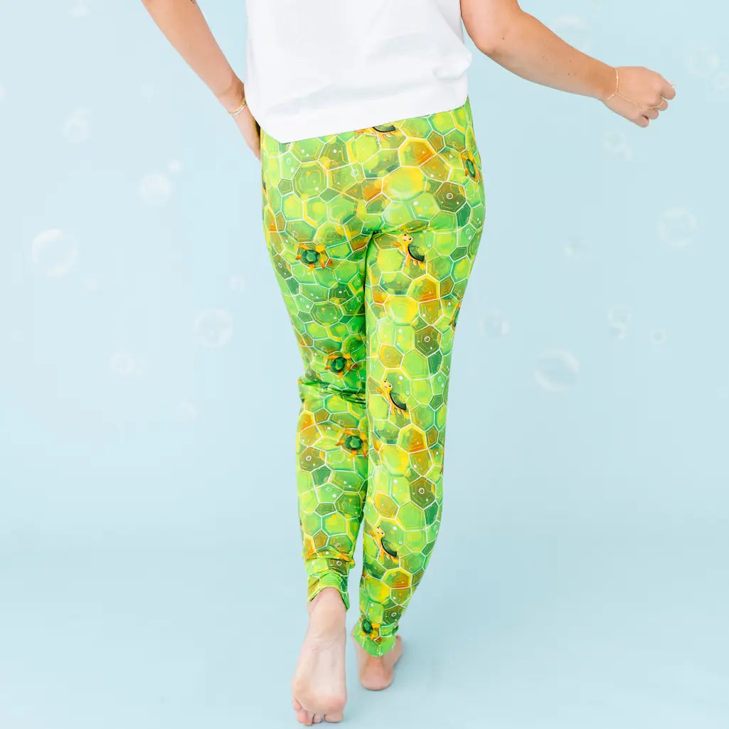 Green and yellow patterned leggings worn by a person on a light blue background.