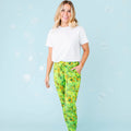 A woman standing and smiling, wearing white shirt and green pajama pants with a geometric turtle pattern.