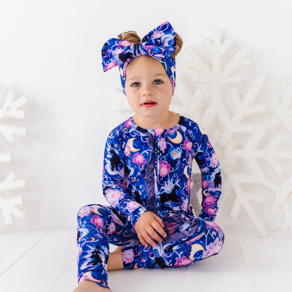 Child wearing a colorful onesie with a floral and moon design on a white background