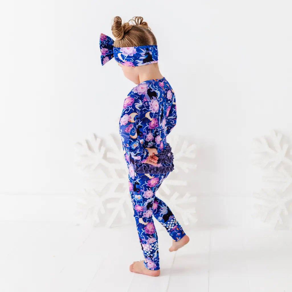 Child wearing a colorful outfit with a floral and animal pattern on a white background