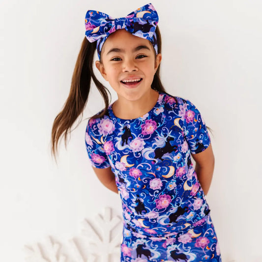 Child wearing a blue floral and unicorn patterned outfit with a matching headband.