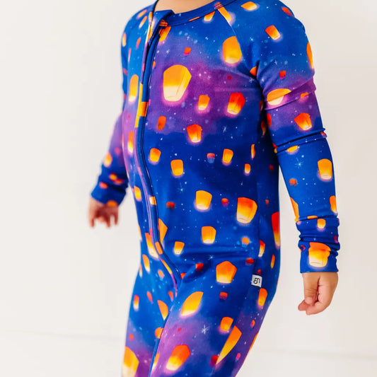 Child wearing a blue onesie with orange lantern pattern on a white background