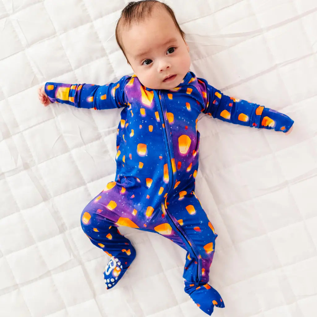 Baby wearing a colorful onesie with orange polka dots on a white textured surface