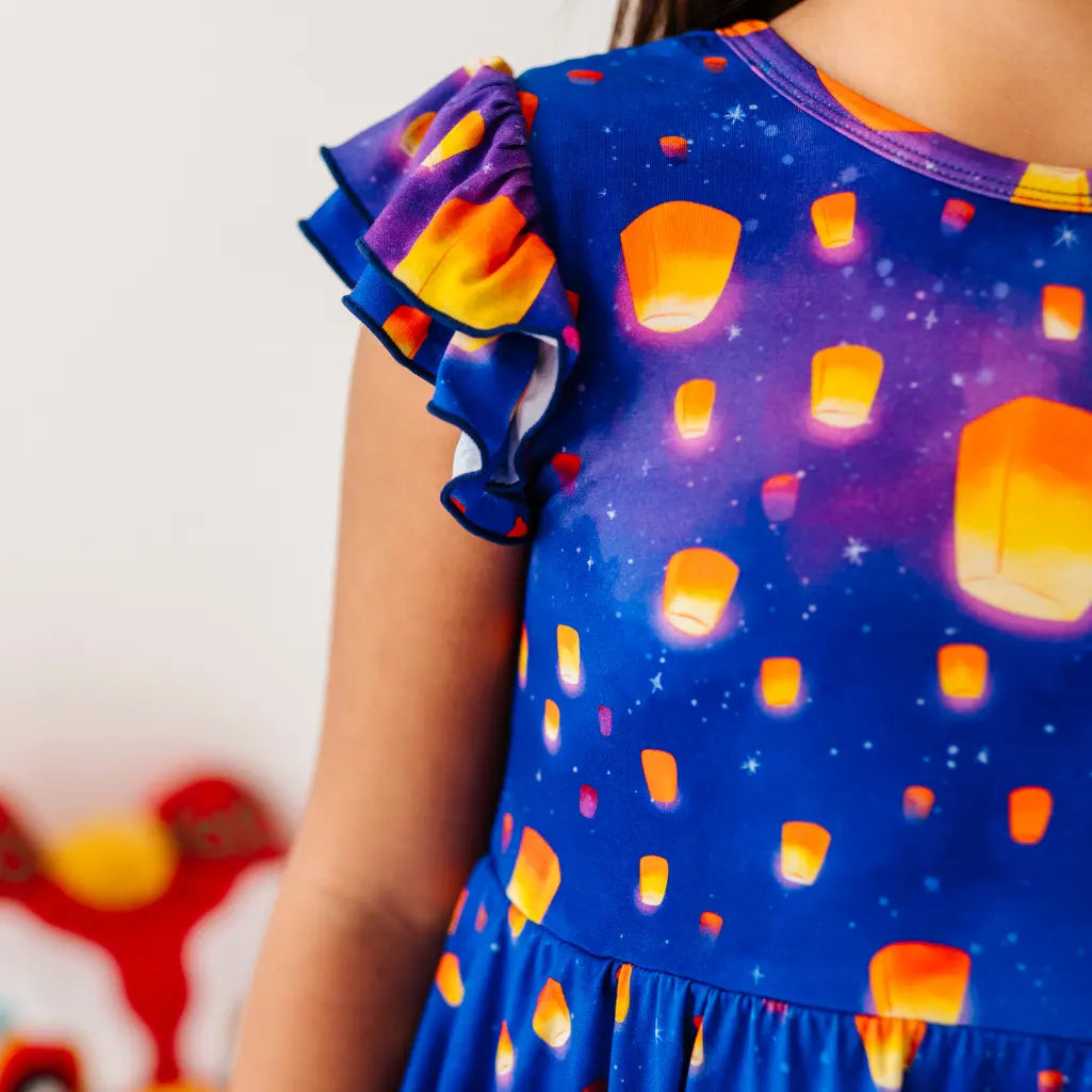Child wearing a dress with sky lanterns design on a white background