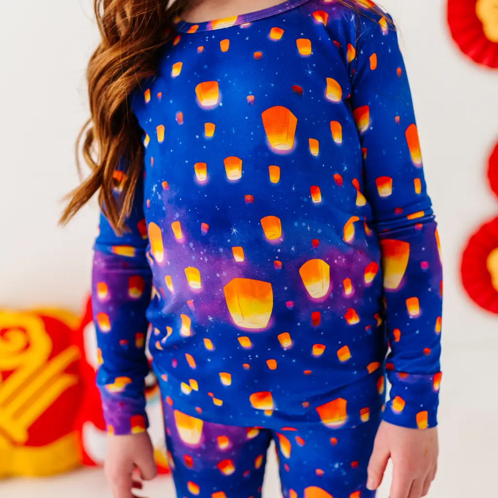 Child wearing a blue pajama set with candy corn pattern, standing against a colorful background.