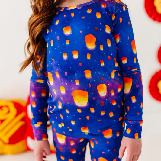 Child wearing a blue pajama set with candy corn pattern, standing against a colorful background.