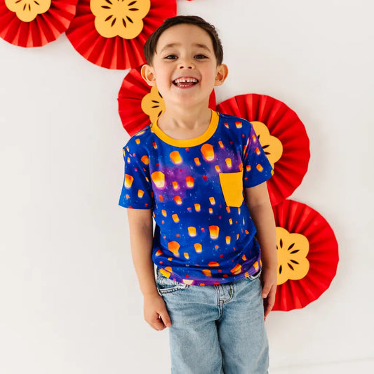 Child wearing a colorful shirt with red and yellow decorations in the background