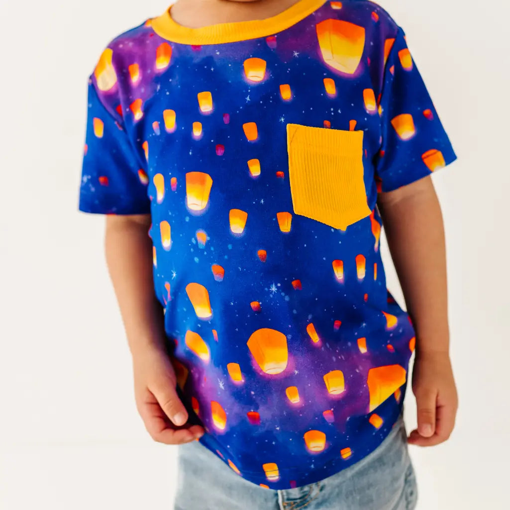 Child wearing a colorful t-shirt with a pattern of orange shapes on a blue background.