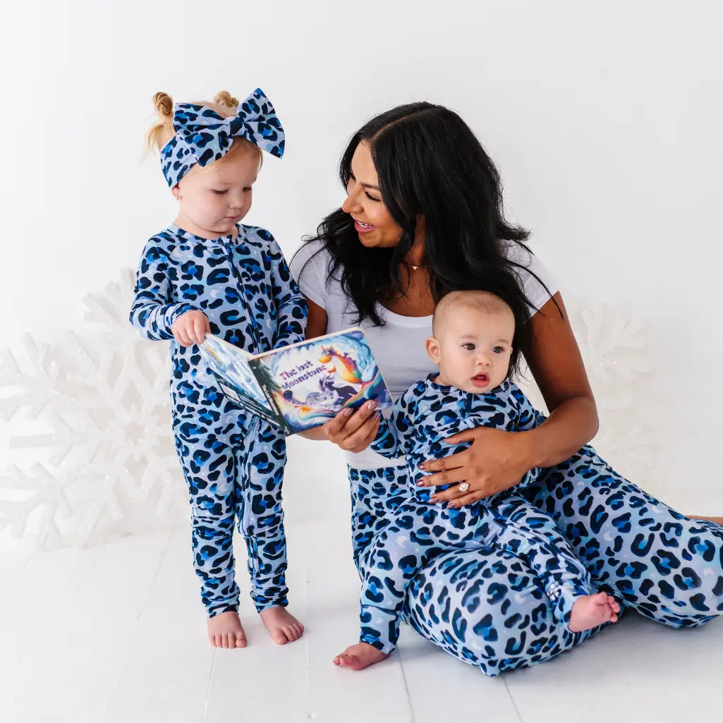 Woman and two children in matching blue and white leopard print outfits on a white background