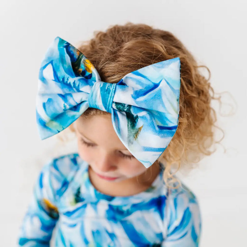 Child wearing a blue and white floral headband with matching outfit on a light background