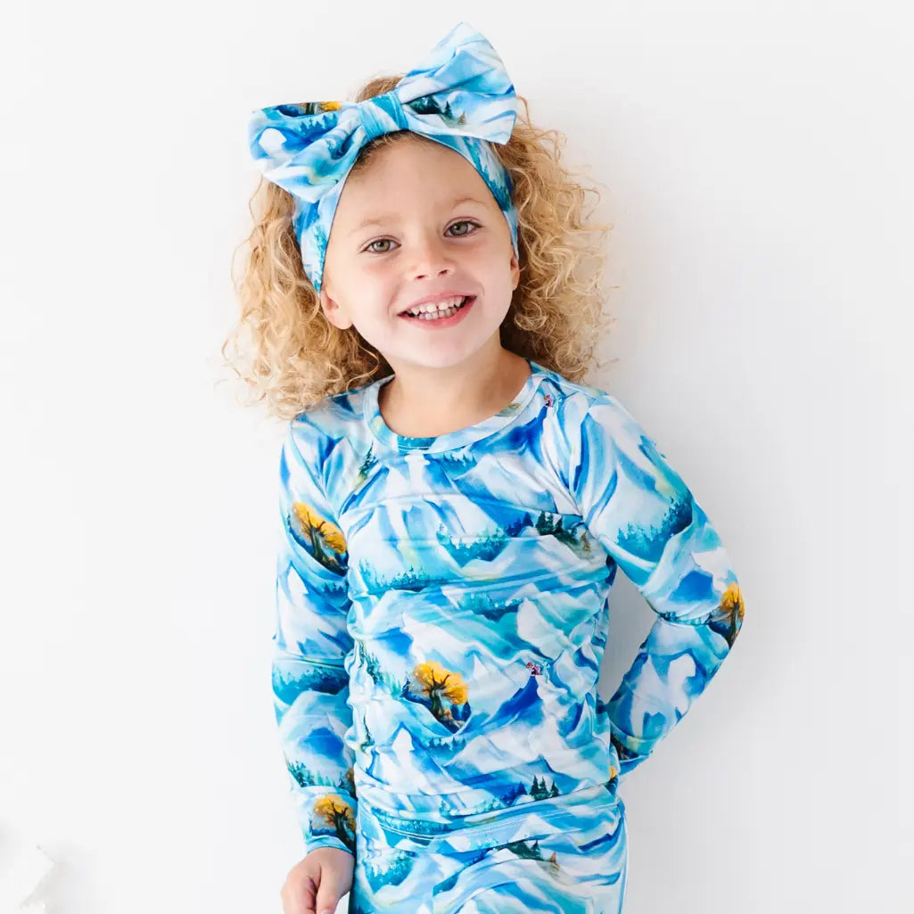 Child wearing a blue and white patterned outfit with a matching headband on a white background