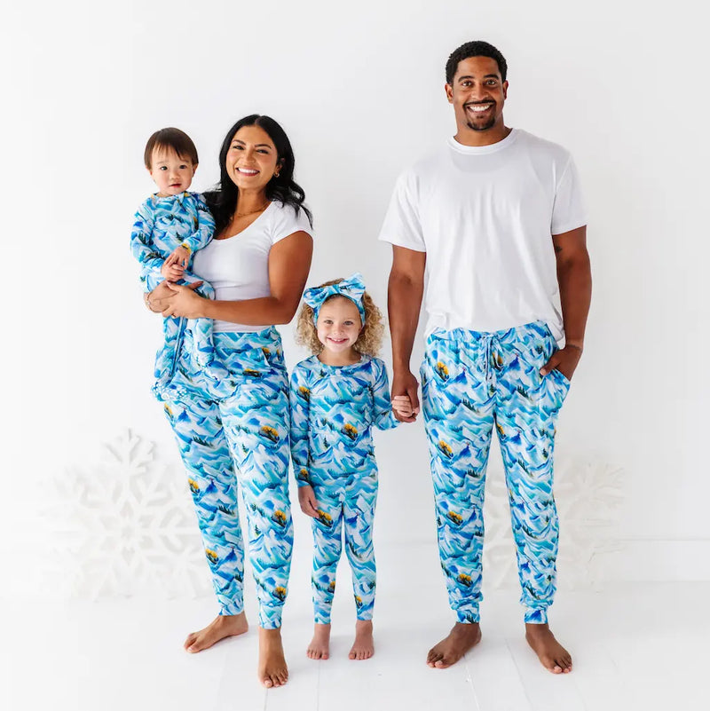 Child wearing an orange and yellow swimsuit with a matching headband on a light blue background