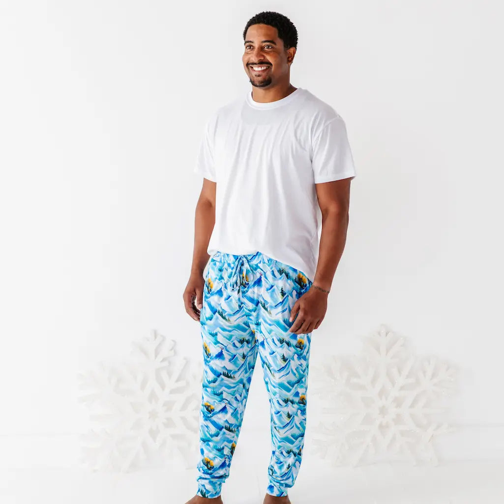 Man wearing a white t-shirt and blue patterned pants on a white background