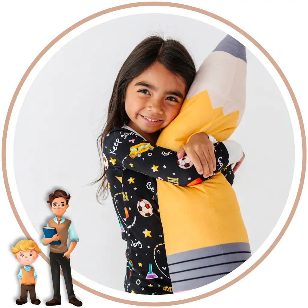 A young girl smiling while hugging a large plush pencil toy. She is wearing a black long-sleeve pajama top with a colorful school-themed print.