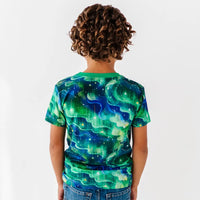 Child wearing a green and blue abstract patterned shirt on a white background