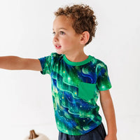 Child wearing a green galaxy-themed t-shirt on a white background